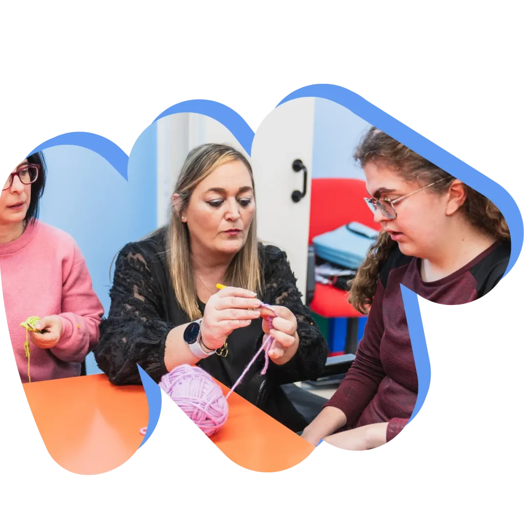 Two disabled girls in knitting class with support worker