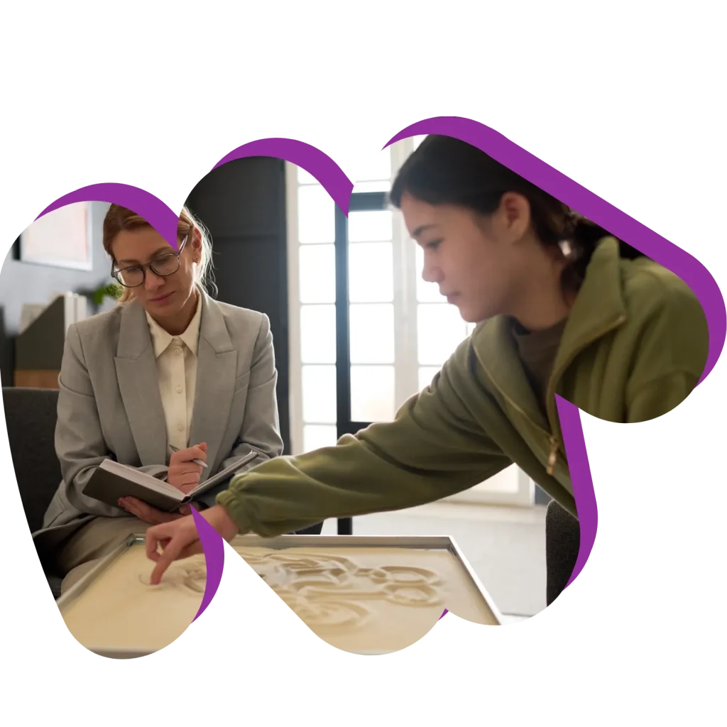 Support worker with girl in sand therapy session